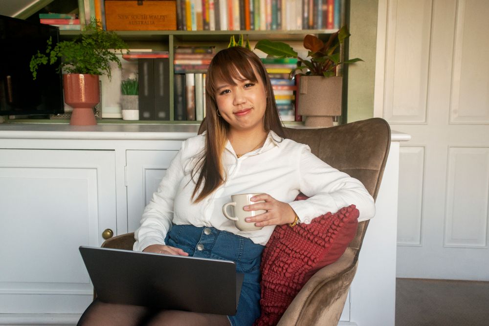 Tan sitting with laptop and cup of coffee