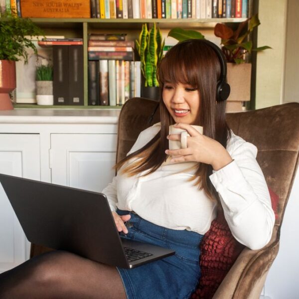 Tan working on a laptop and drinking coffee