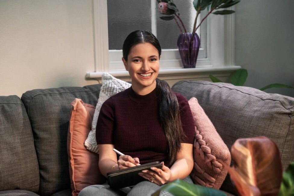 Student, Nika, sitting on sofa, writing in notepad