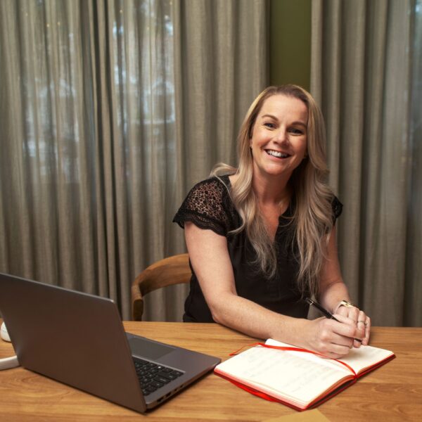 Western Sydney Online student studying online and writing in a red notebook